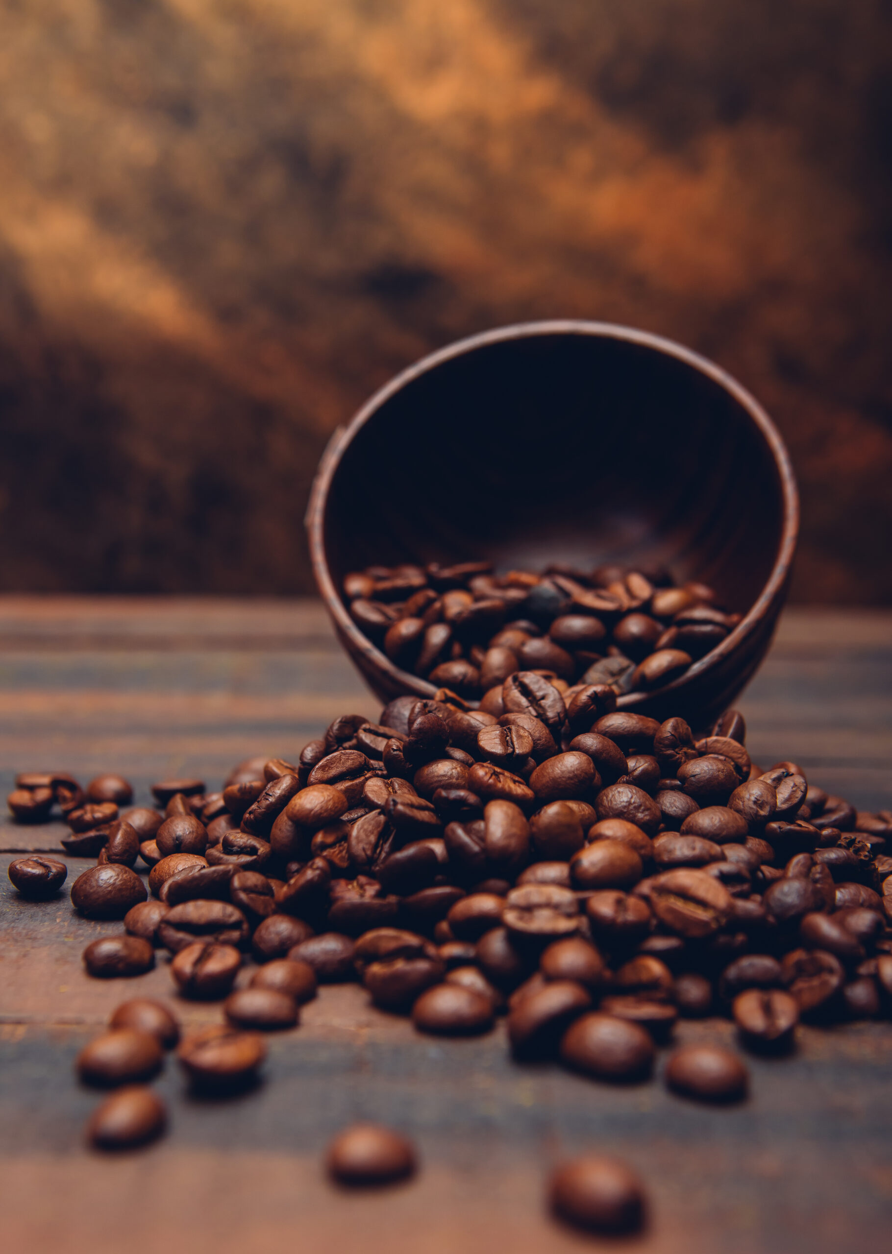 Dark coffee beans in a bowl on a brown background. side view.